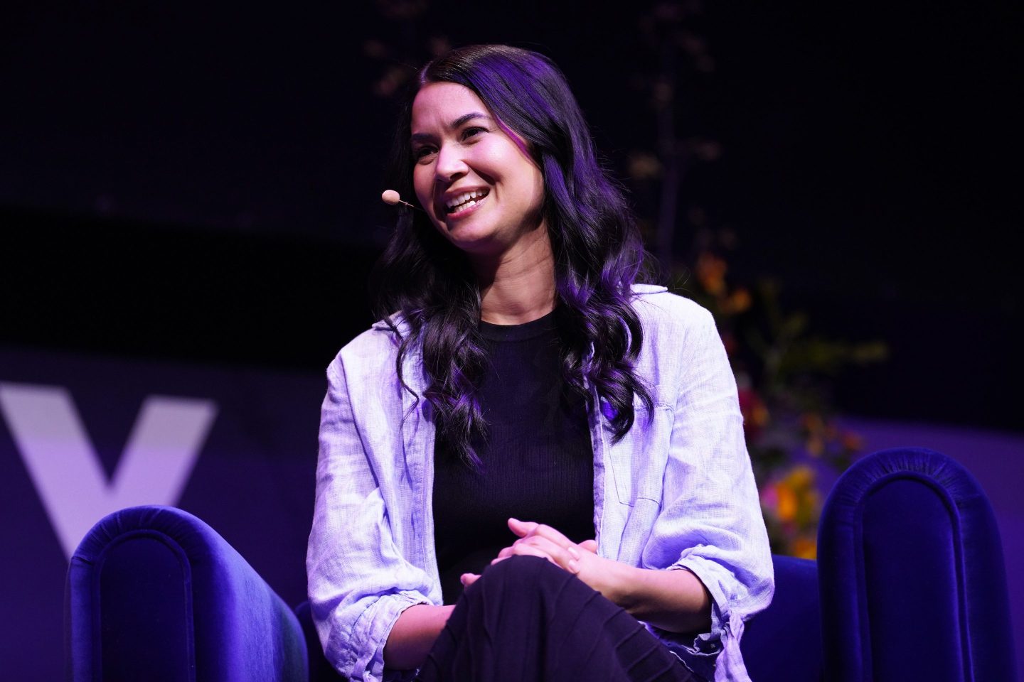 Melanie Perkins spricht in einem Canva-Büro, während KI-Grafiken auf dem Bildschirm zu sehen sind.