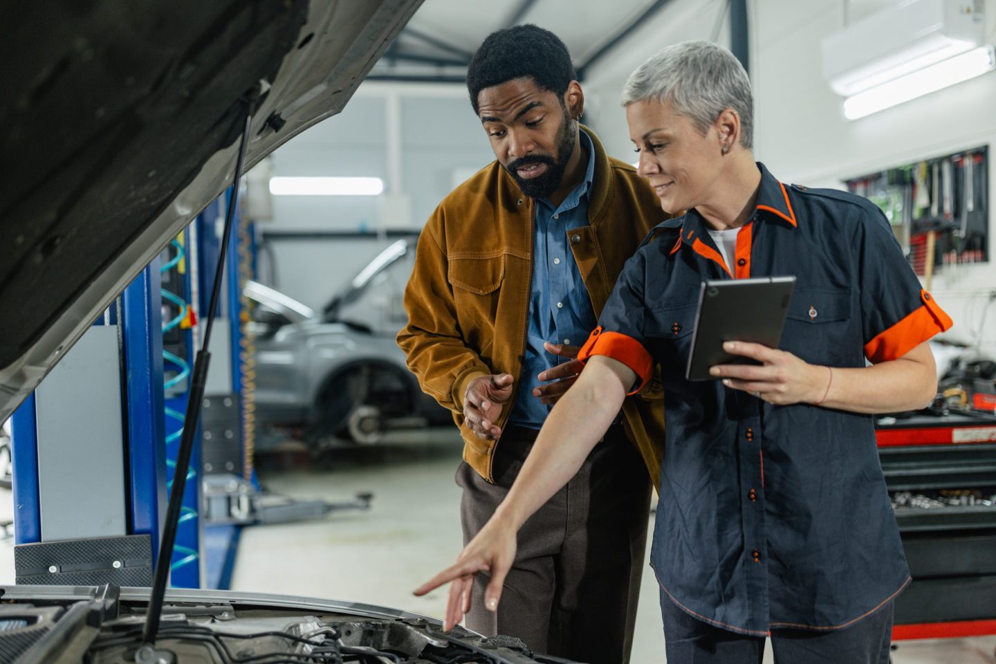 Servicehalle mit Technikern, die an einem Fahrzeug arbeiten