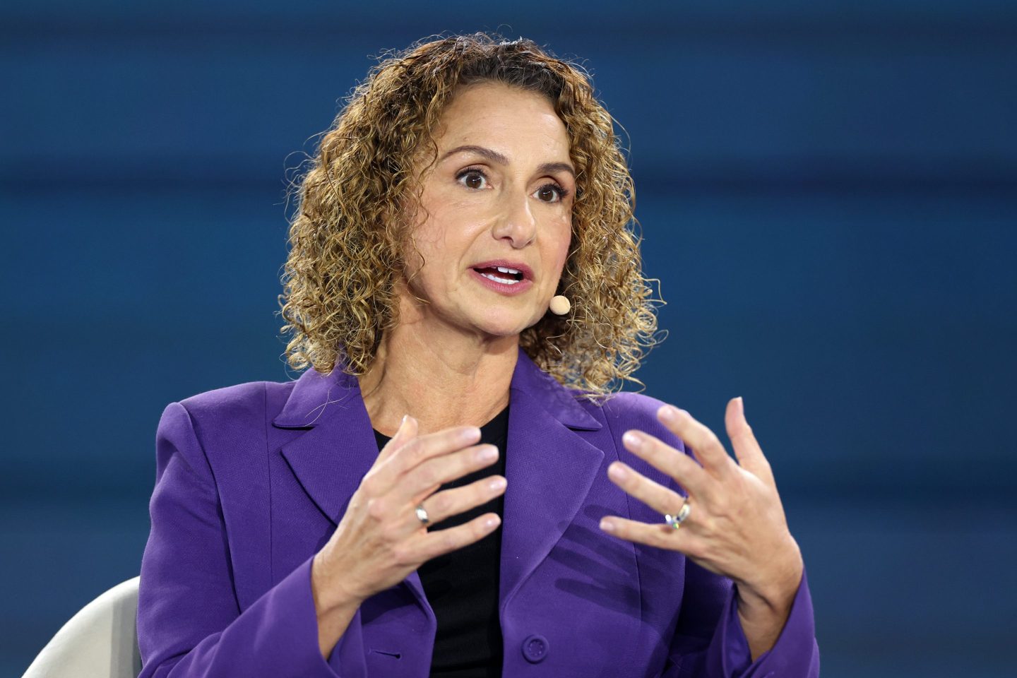 Lila Ibrahim speaking at a technology conference, with a backdrop of DeepMind branding