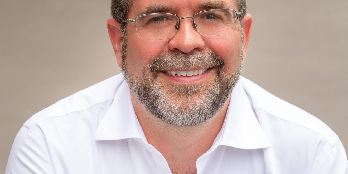 Ein 55-jähriger ehemaliger Tech-PR-Manager steht in einem Klassenraum einer Highschool und spricht die Schüler an.