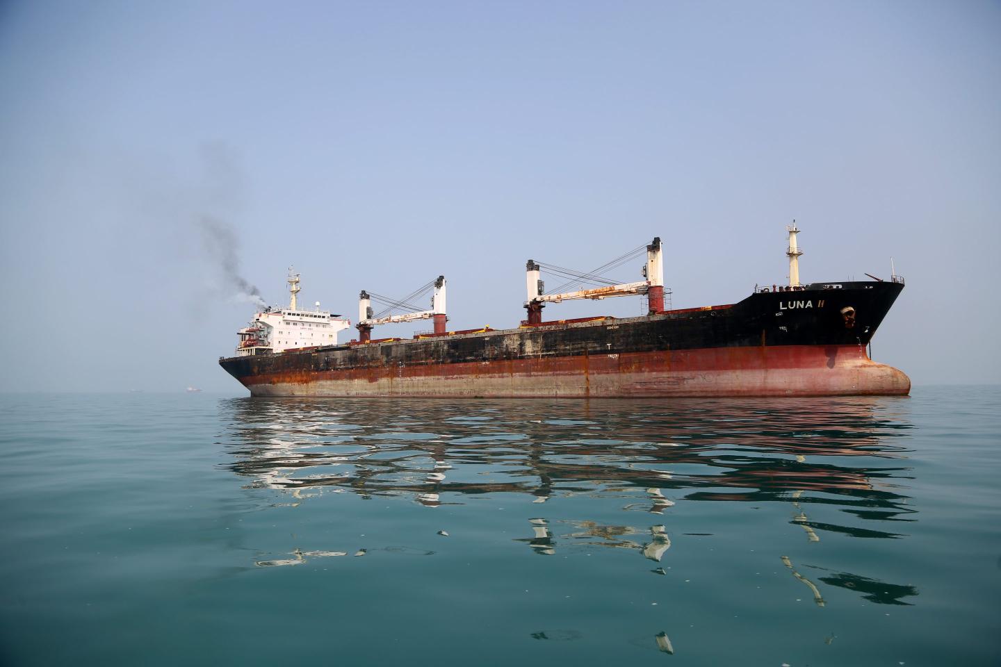 Barrels of crude oil and diesel against a backdrop of the Strait of Hormuz